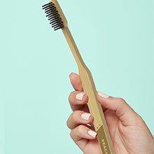 A hand holding the bamboo toothbrush